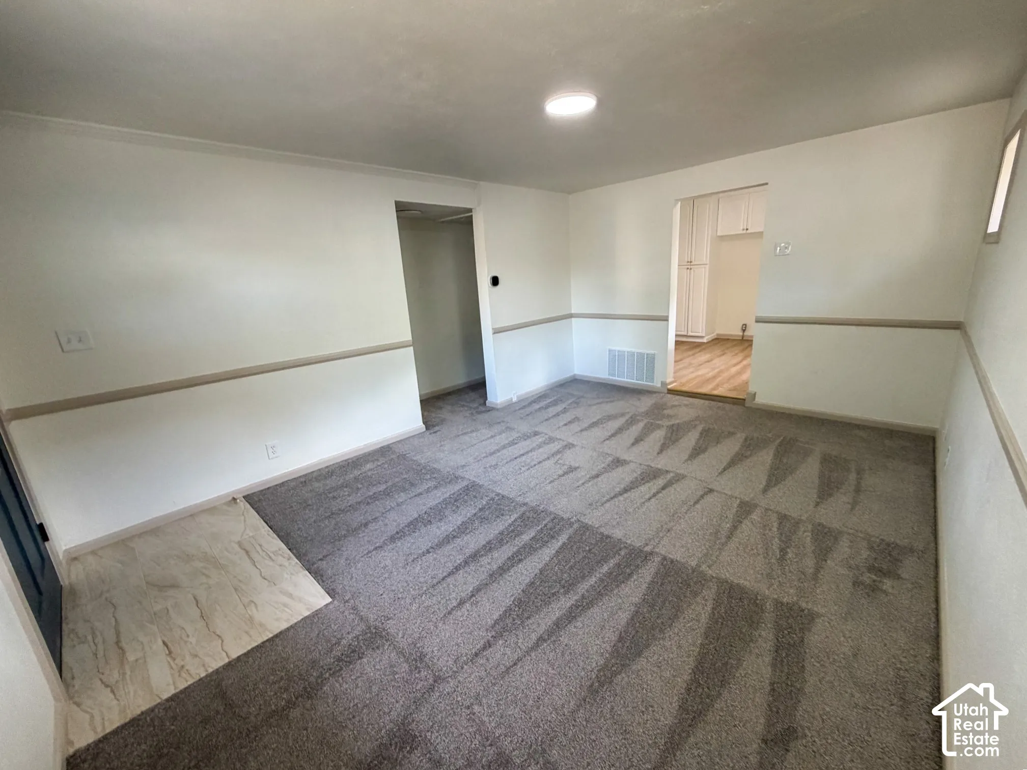Recessed lighting illuminates the carpeted living area with chair rail molding and an entryway featuring wood-finish flooring