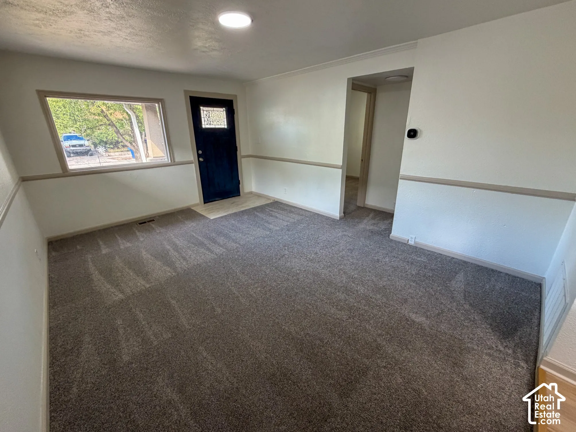 Recessed ceiling light, wall-to-wall carpeting, and a dark entry door with decorative glass inlay