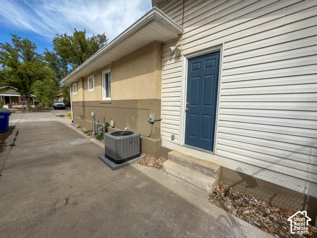 Two-tone exterior with stucco and siding finishes, featuring a dark blue entry door, concrete steps, and a concrete driveway