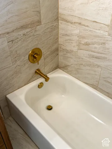Soaking tub with brass-finish fixtures and stone-look tiled surround