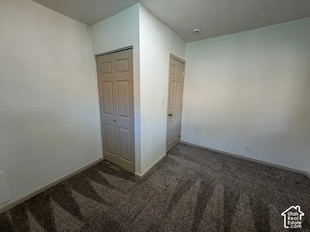 Interior space featuring textured walls, carpet flooring, a bifold closet door, and an additional standard door
