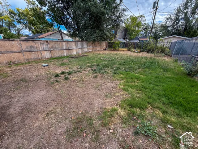Expansive lot featuring varied ground cover, mature trees, and a perimeter fence