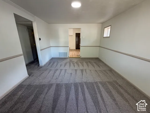 Recessed ceiling light, neutral wall colors, chair rail molding, patterned carpet flooring, and a window for natural light