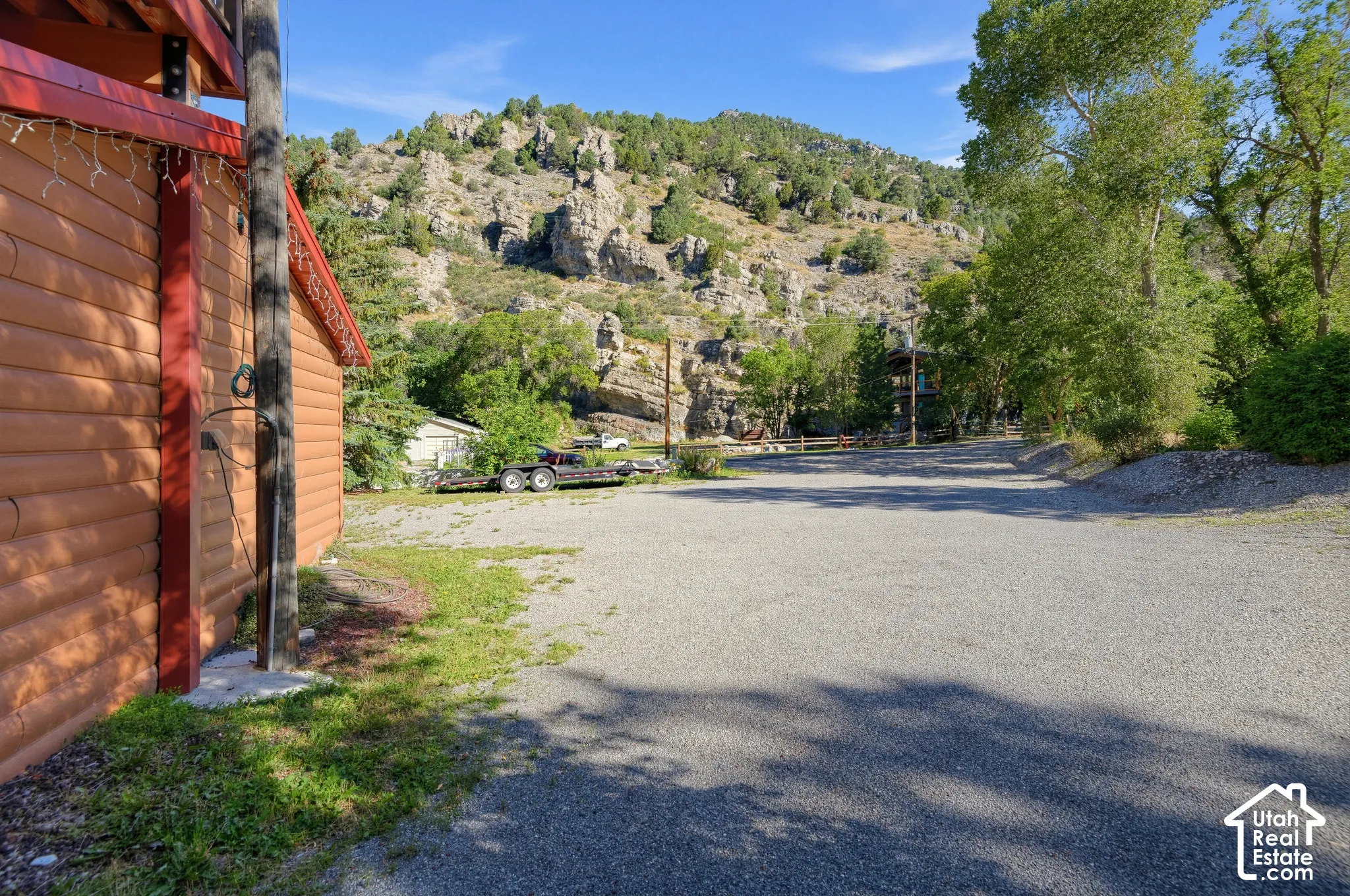 Gravel parking area bordered by natural landscaping and mature trees