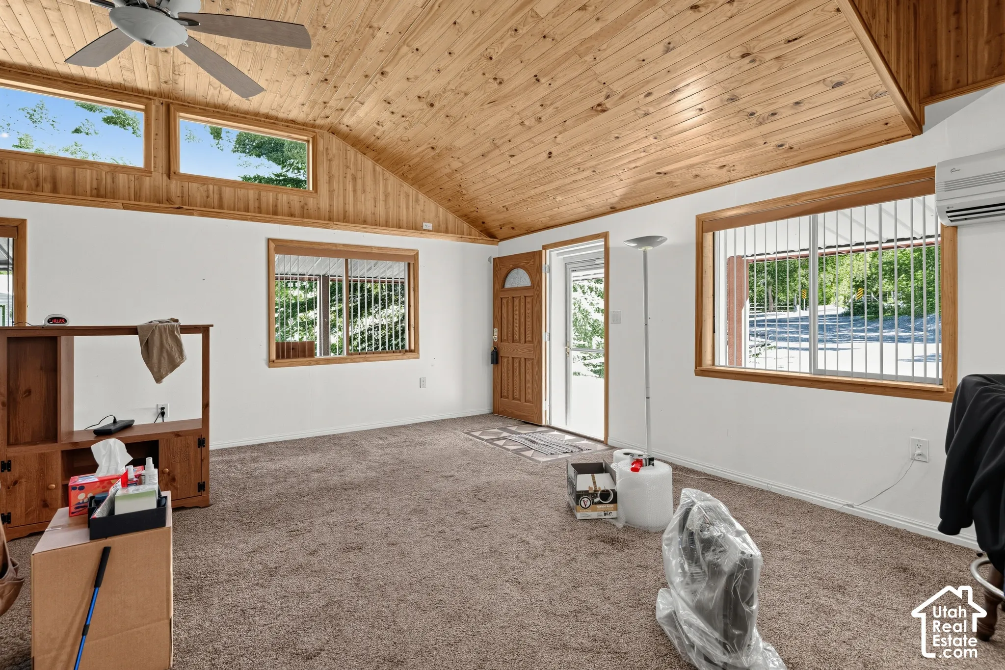 Vaulted wood-finish ceiling, wood-trimmed windows, and a ceiling fan with integrated lighting