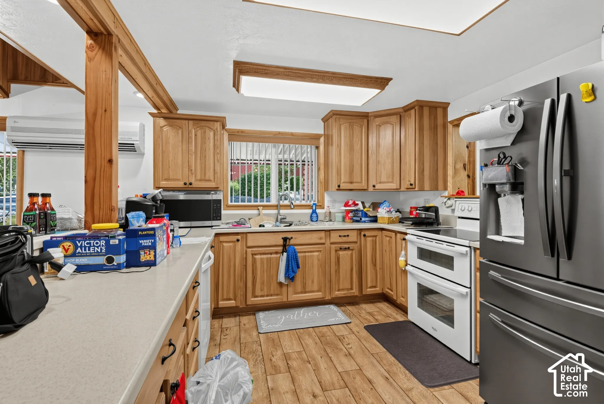 Kitchen featuring wood-finish flooring, light-toned cabinetry, solid surface countertops, and exposed wooden beams
