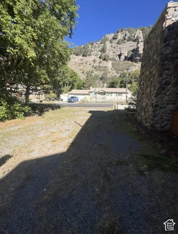 Stone exterior wall with a gravel driveway and mature tree