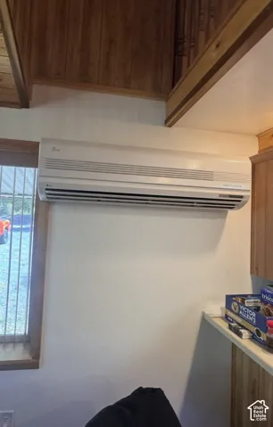 Split-system air conditioning unit with a wood-paneled ceiling and exposed wood beams