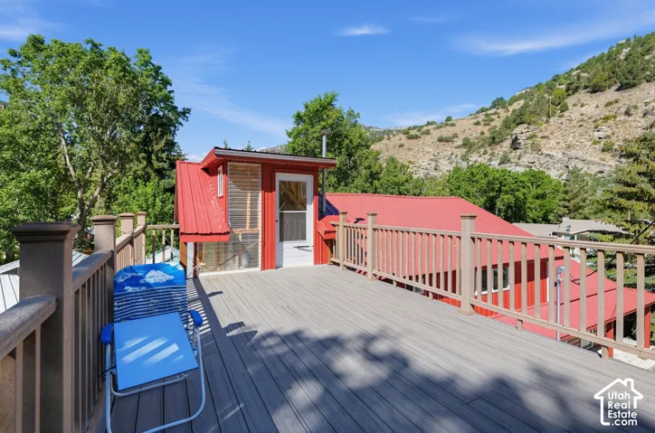 Expansive outdoor deck with composite decking and railing, offering a mountain backdrop and a red metal-roofed structure