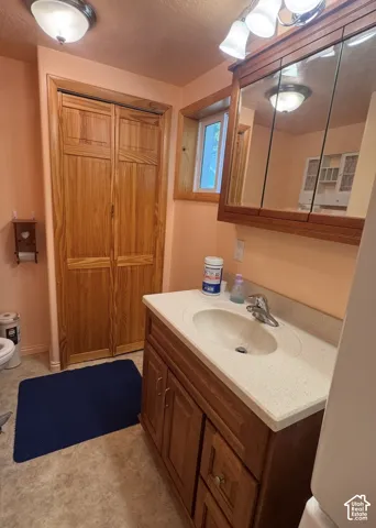 Vanity with integrated sink and chrome faucet, wood-finish cabinetry, and built-in medicine cabinet with mirror