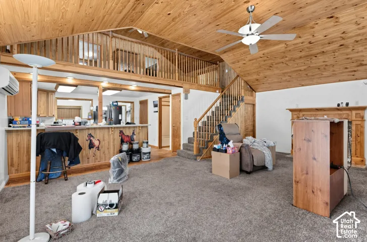 Angled wood-paneled ceiling, wood-finish flooring, wood staircase with railing, wooden fireplace mantel, and recessed lighting