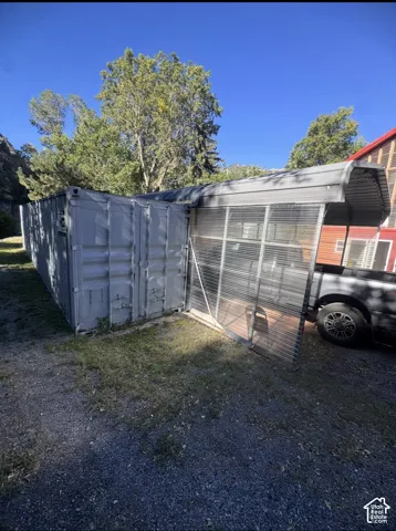 Gravel ground cover with a shipping container structure and an attached metal carport