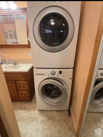 Stacked washer and dryer unit, wood-finish vanity with an integrated sink, and an overhead medicine cabinet with a mirror