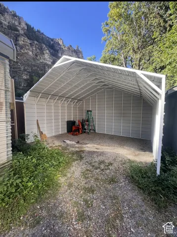 Metal carport with a peaked roof and gravel flooring