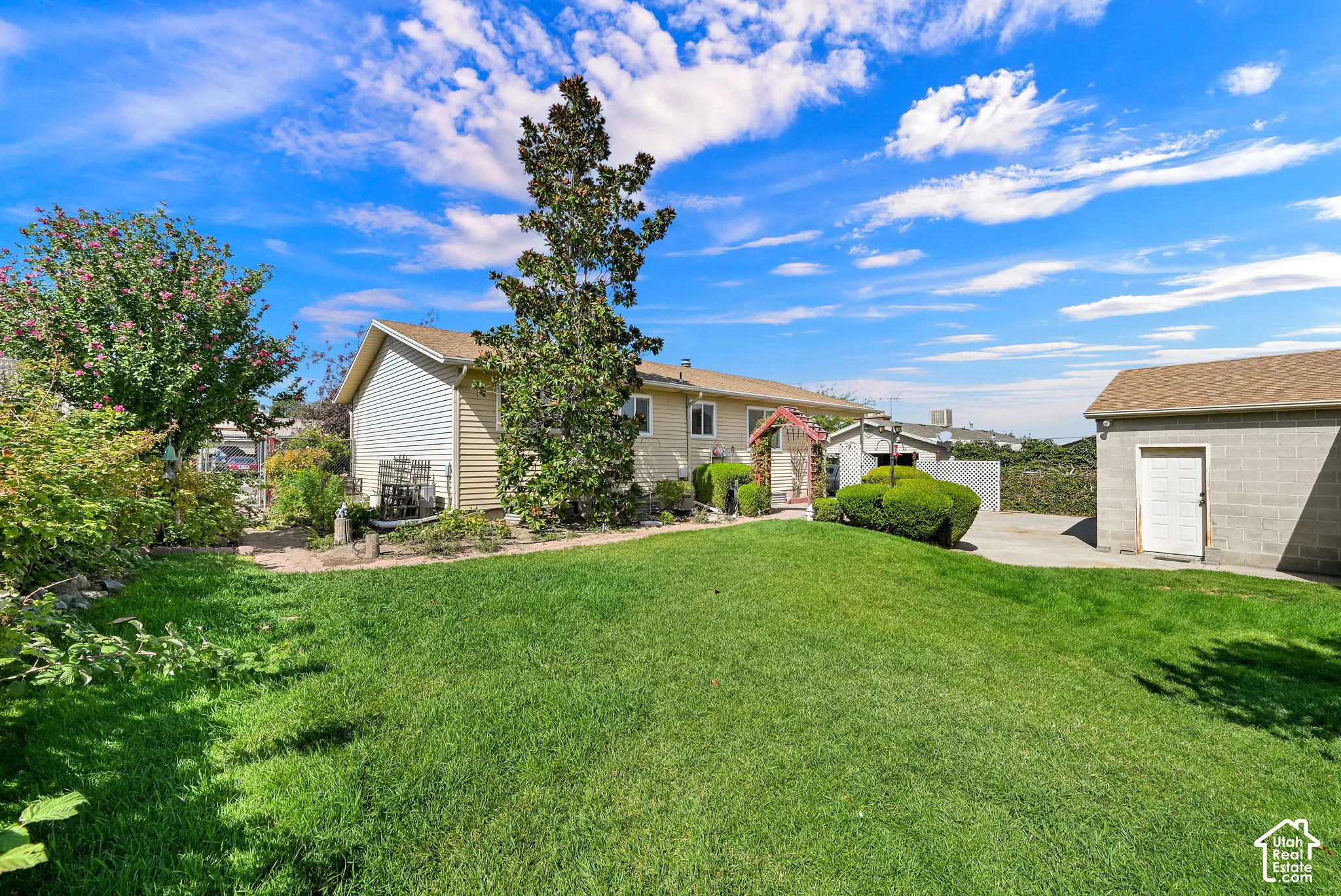 Expansive green lawn, mature trees, and a detached garage