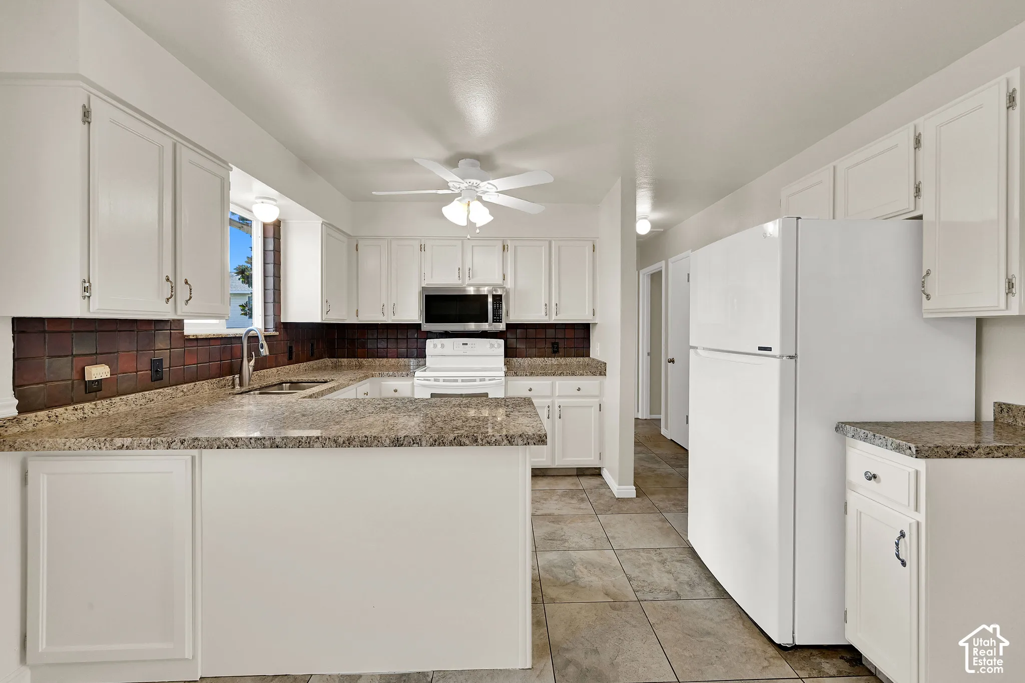 Kitchen featuring white cabinetry, stone-look countertops, a tile backsplash, and tile flooring - refrigerator is included