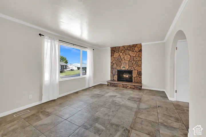 Stone-clad fireplace with hearth, tile flooring, and an arched doorway