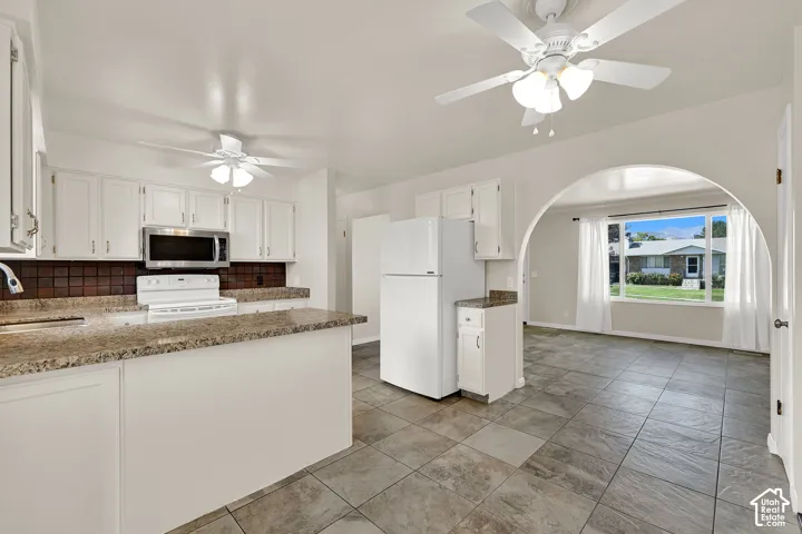 Kitchen featuring white cabinetry, a stainless steel microwave, granite  countertops, and tile flooring