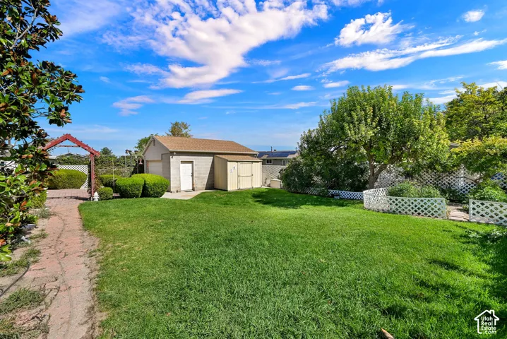 Expansive lawn area with a detached garage and an additional storage shed