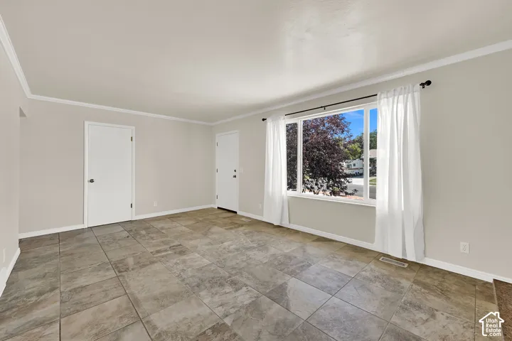 Spacious living room featuring tile flooring, white trim, and a large window with white drapes