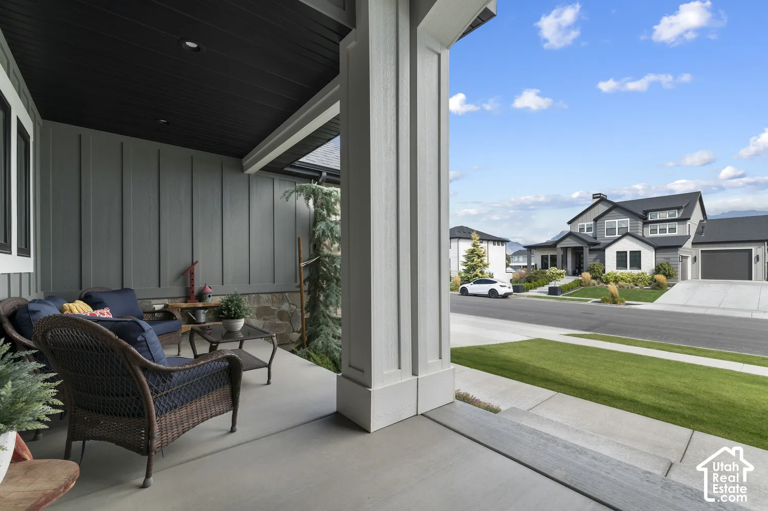 Covered front porch featuring a dark wood-finish ceiling, board and batten siding, and a stone foundation
