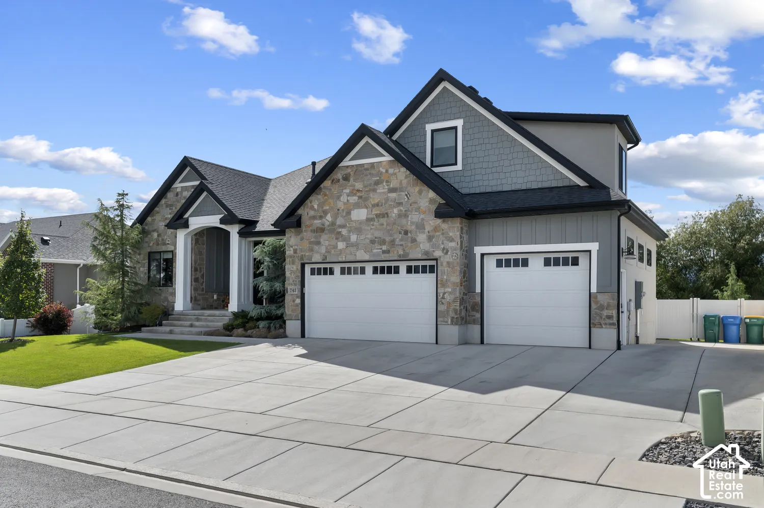 Stone and board-and-batten exterior with an arched entryway, two-car garage, and concrete driveway