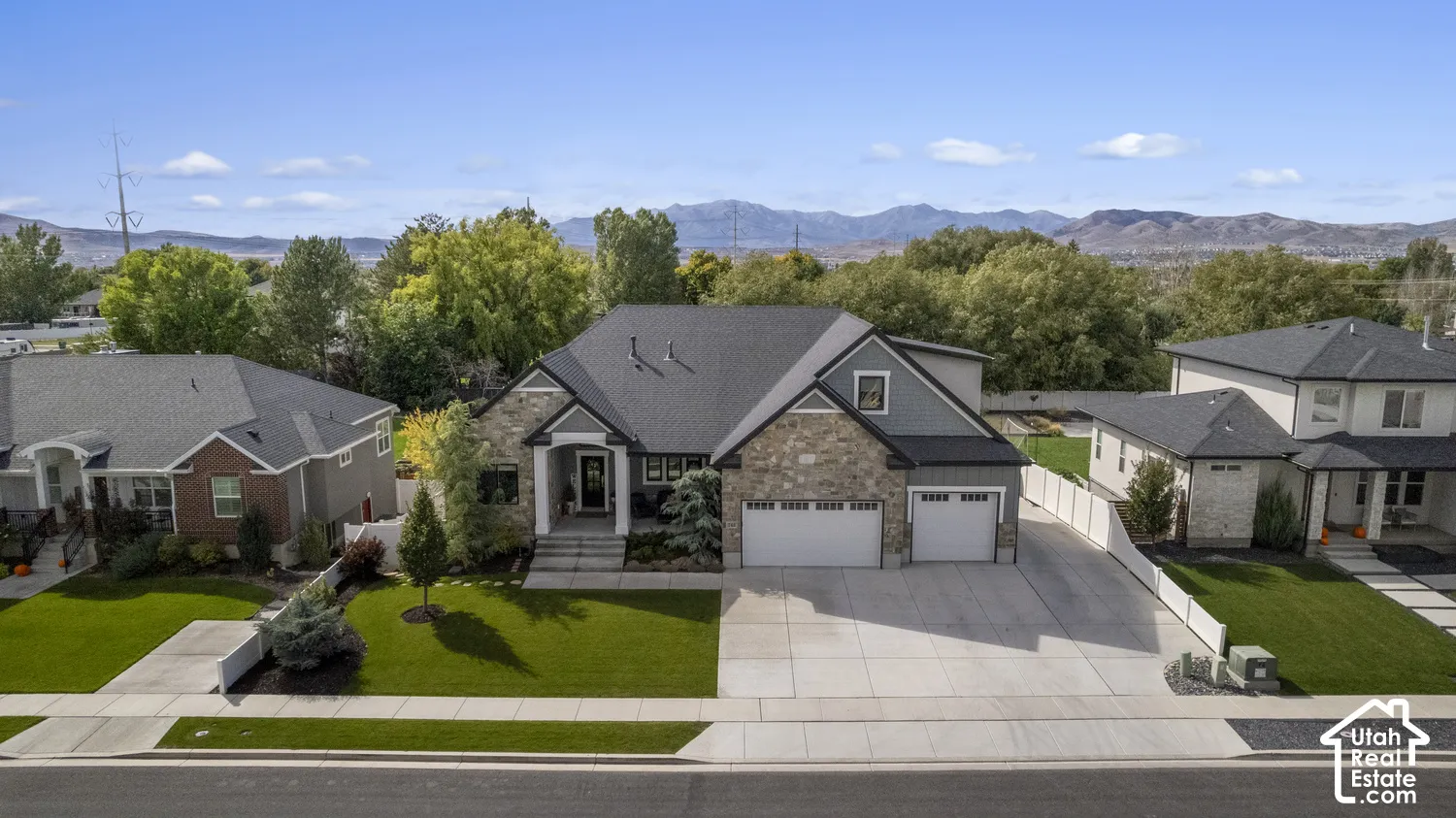 Contemporary residence with a multi-textured facade including stone and siding, a two-car garage, and a concrete driveway