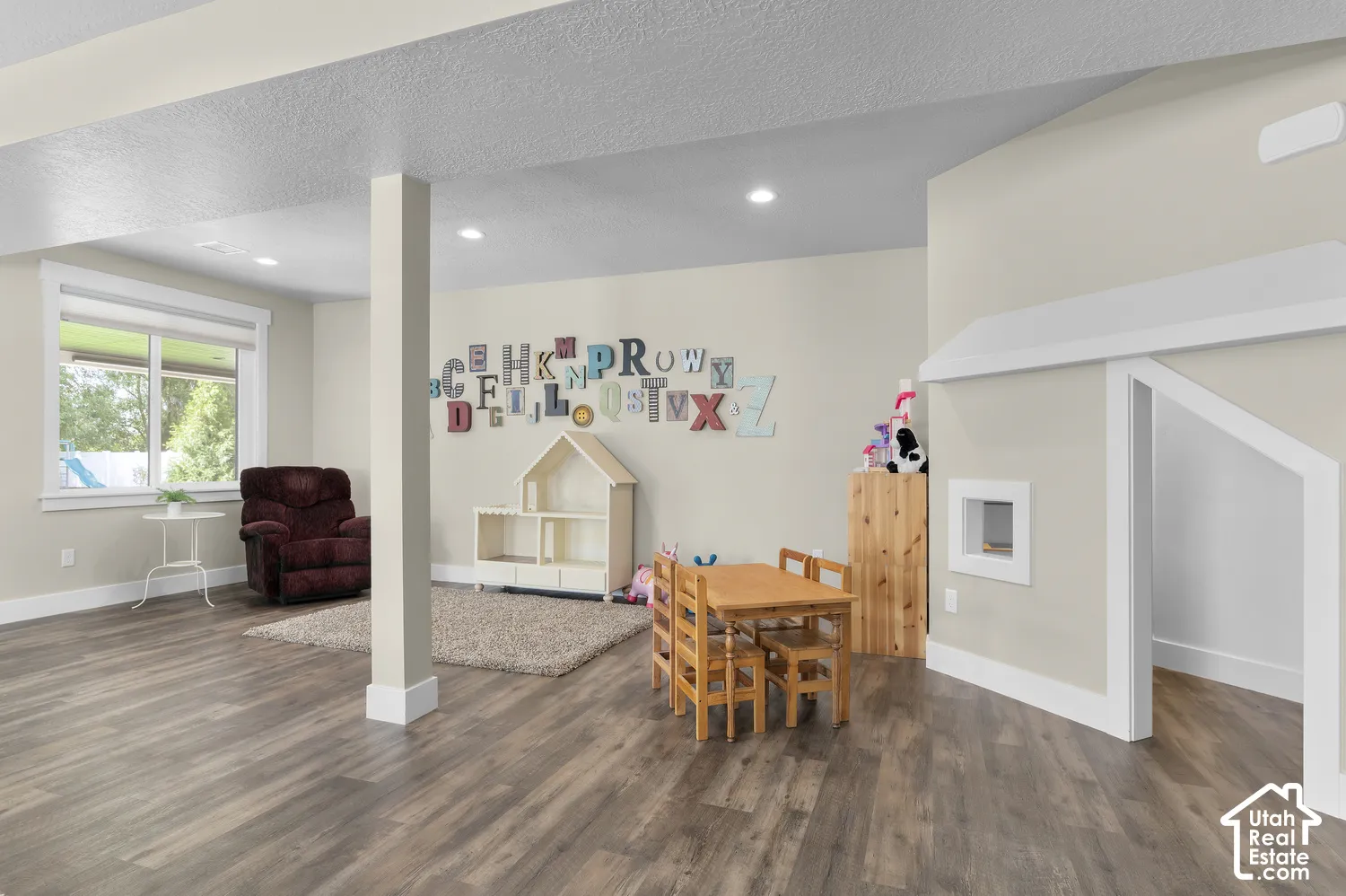 Recessed lighting, wood-finish flooring, and a large window with white trim