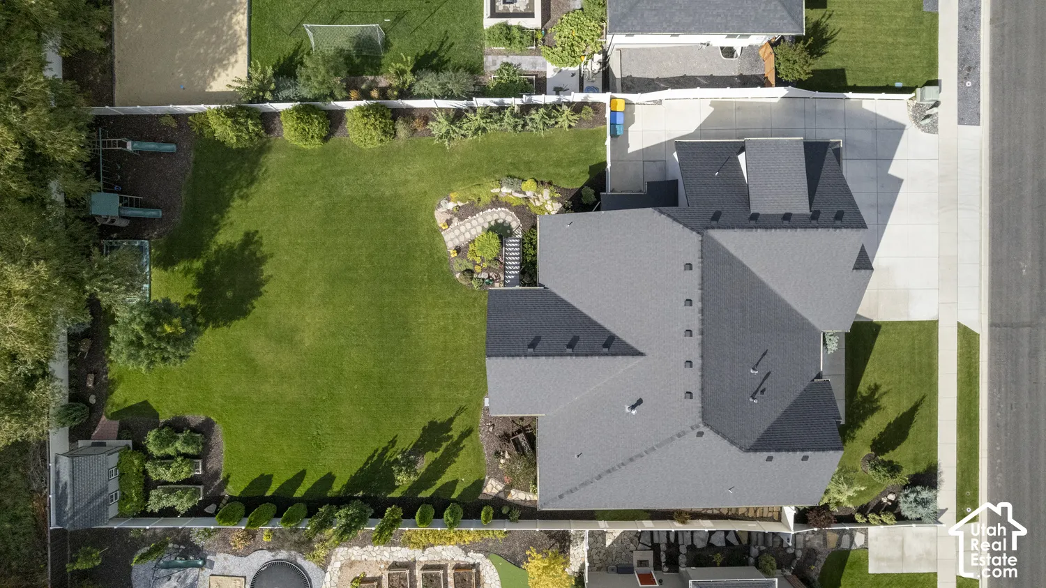 Expansive backyard featuring a manicured lawn, paved patio areas, and mature landscaping