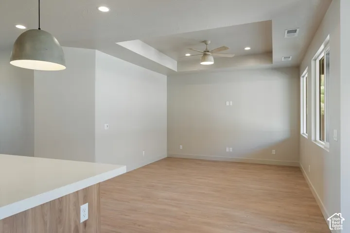 Recessed lighting, wood-finish flooring, tray ceiling, ceiling fan, and multiple windows