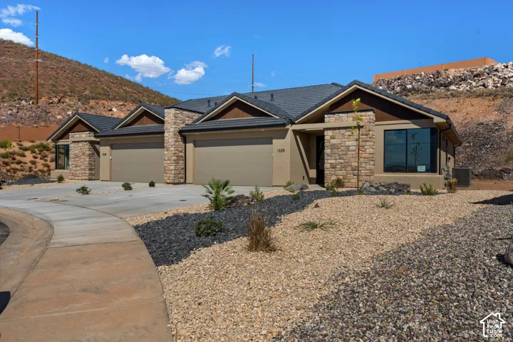Stucco exterior with stone accents, dark-tiled roofing, and integrated garages