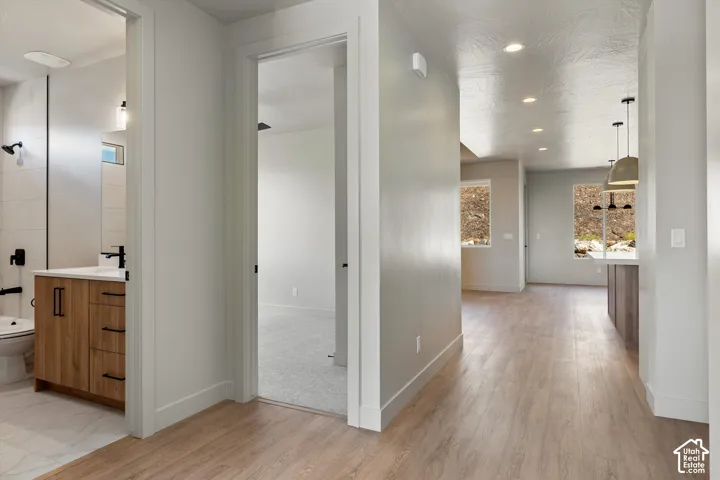 Wood-finish flooring throughout the main corridor, recessed lighting, and a kitchen island with pendant lighting