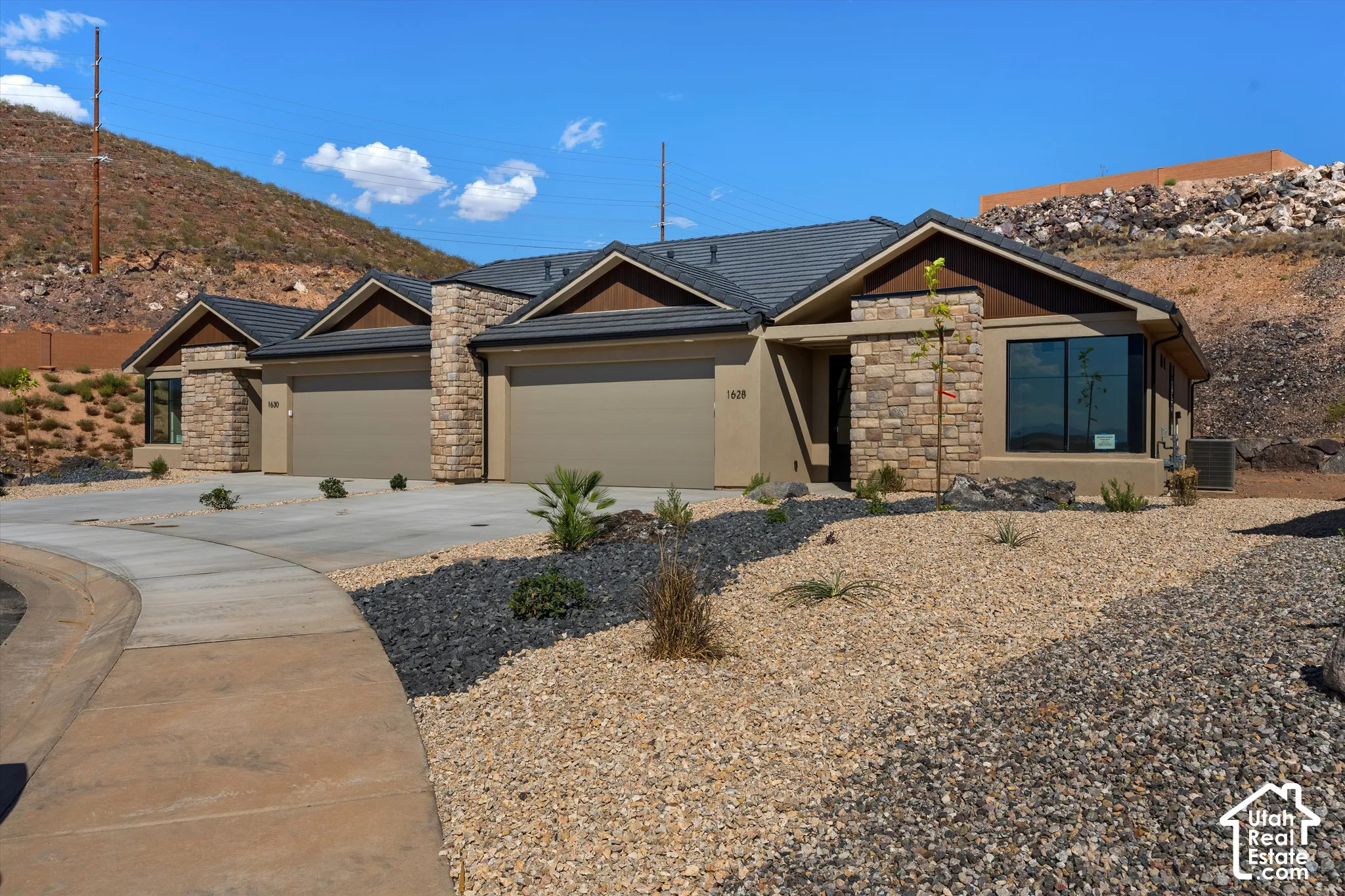 Contemporary exterior design featuring a dark tile roof, stone accents, and stucco siding