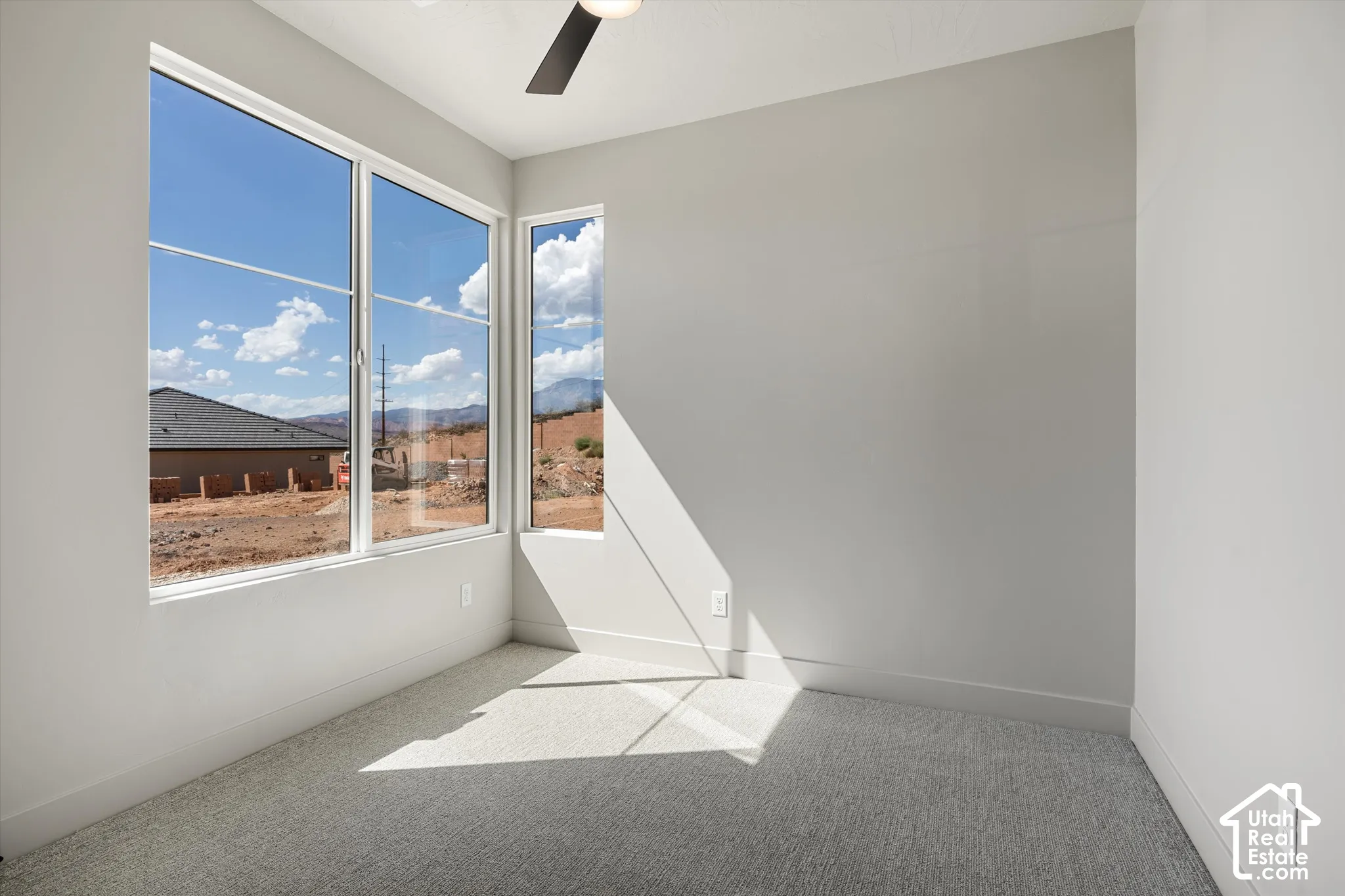 Expansive windows, ceiling fan, neutral wall tones, and carpeted flooring