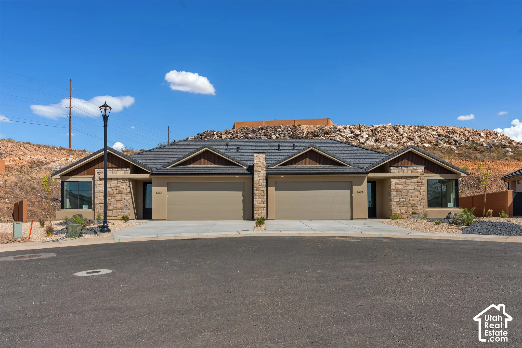 Stone veneer facade with contrasting soffit and fascia, individual garage doors, and front entryways