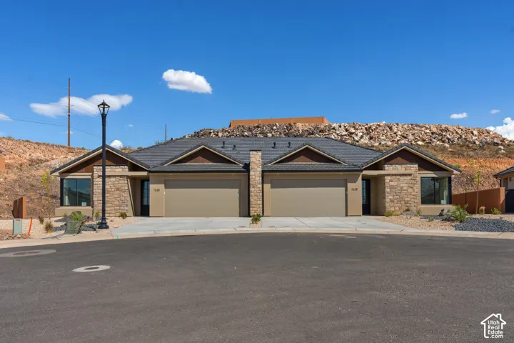 Stone veneer facade with contrasting soffit and fascia, individual garage doors, and front entryways
