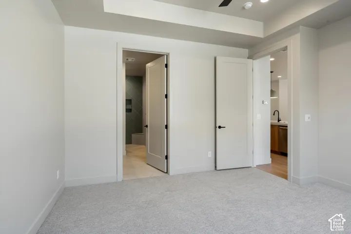 Plush carpeted flooring, tray ceiling, recessed lighting, and solid core doors with black hardware