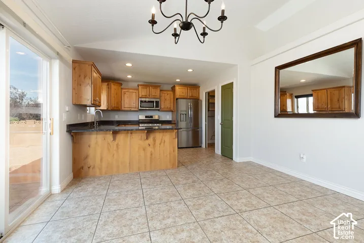 Kitchen featuring wood-finish cabinetry, stainless steel appliances, dark countertops, and a breakfast bar