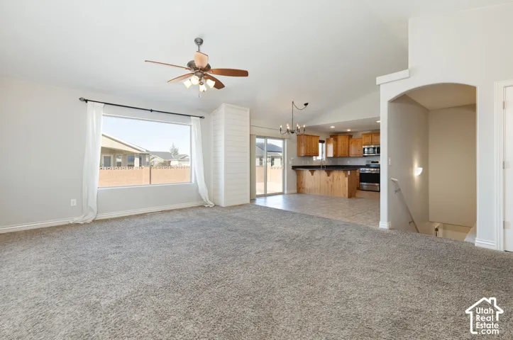 Vaulted ceiling with a ceiling fan, broad window, and shiplap accent wall