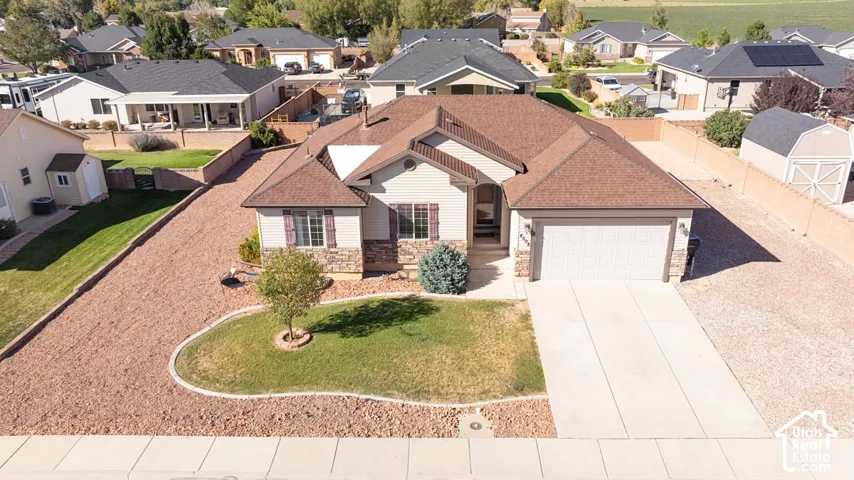 Single-story residence featuring a two-car garage, stone facade accents, and a front yard with a landscaped planter