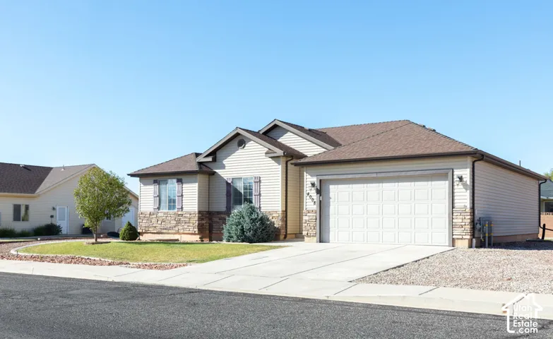Exterior featuring siding and stone facade, an attached garage, a concrete driveway, and a landscaped front yard