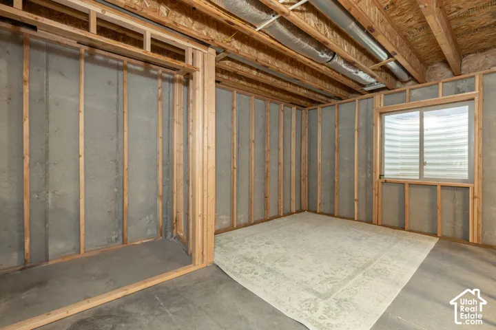 Framed interior walls, exposed concrete foundation, visible ceiling joists, and a window with a well-style enclosure
