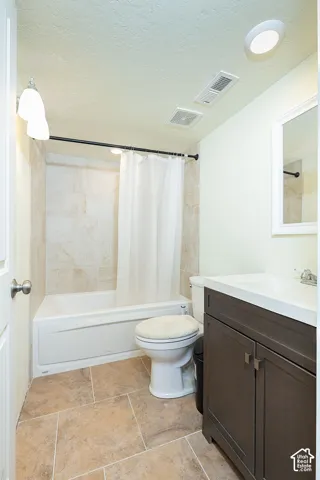 Bathroom featuring a built-in tub with tile surround, a built-in vanity with an integrated sink, a wall-mounted mirror, and tile flooring