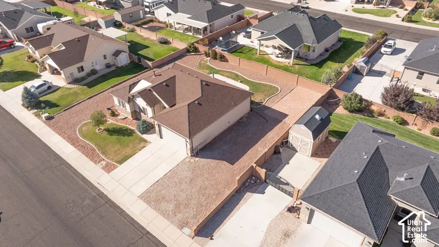 Residence featuring a two-car garage, gravel landscaping, a fenced backyard, and an exterior storage shed