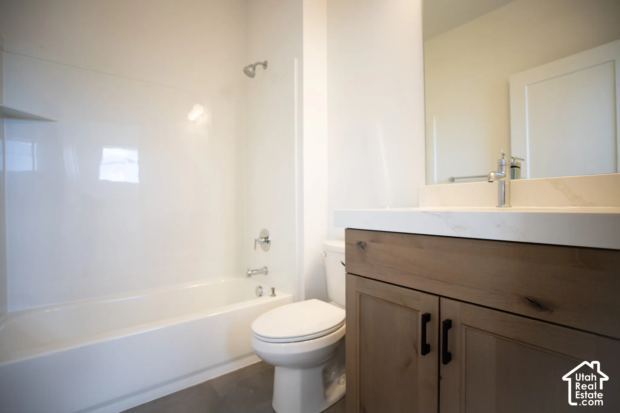Full secondary bath with stained wood cabinets and quartz slab countertops.