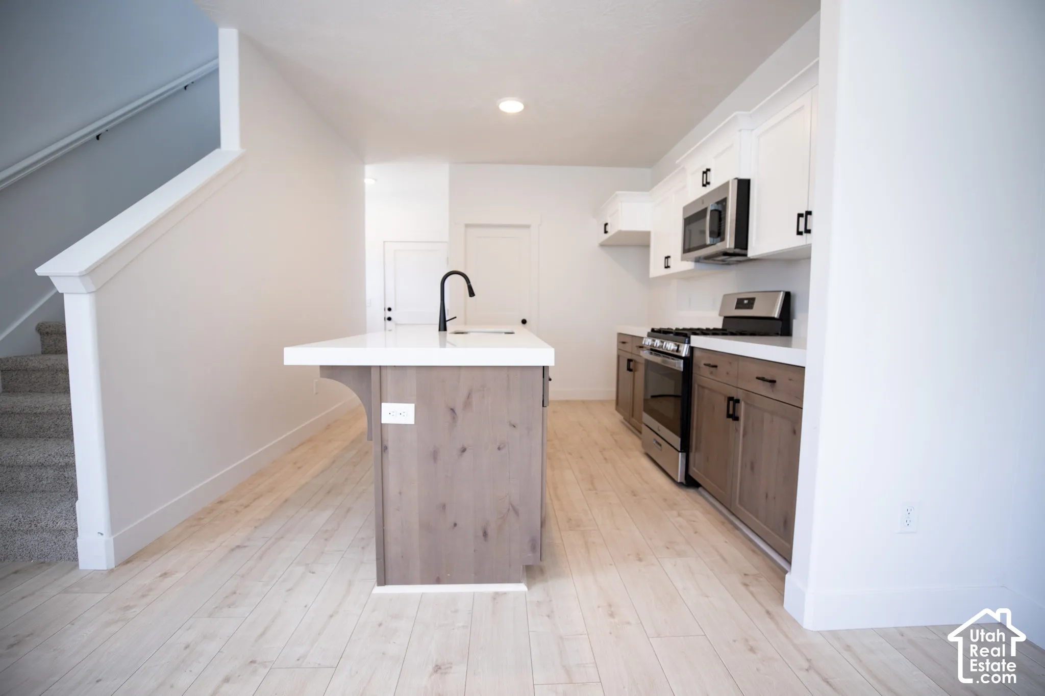 Terrific kitchen with white painted wood uppers,, stained wood lowers and island, quartz slab countertop, gas range, dishwasher, microwave, disposal and walk-in pantry.