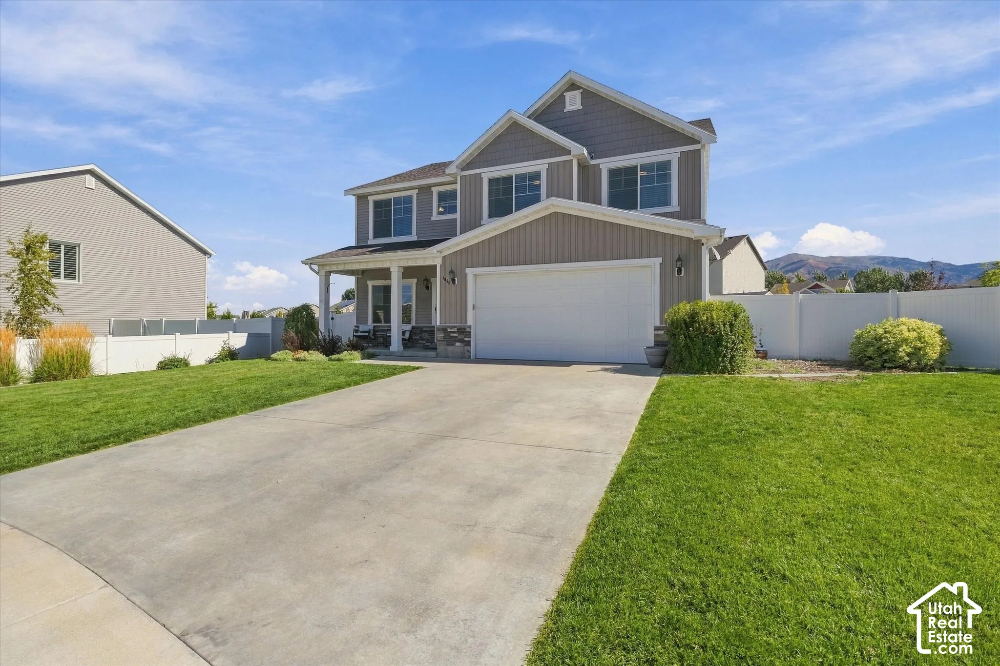Two-story residence with a covered front porch featuring stone accents, a two-car garage, and a concrete driveway