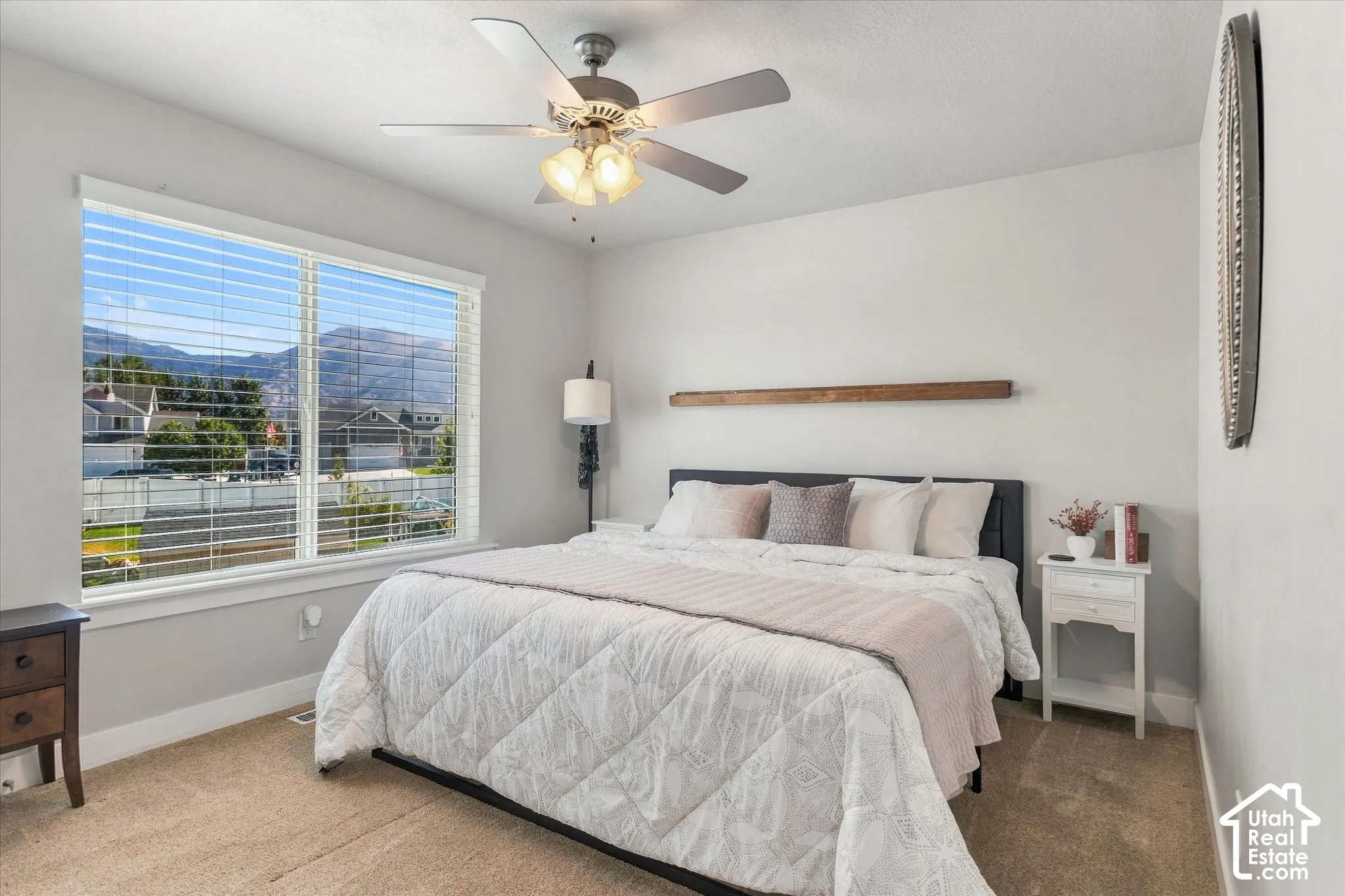 White walls complemented by carpet flooring and a ceiling fan with integrated lighting