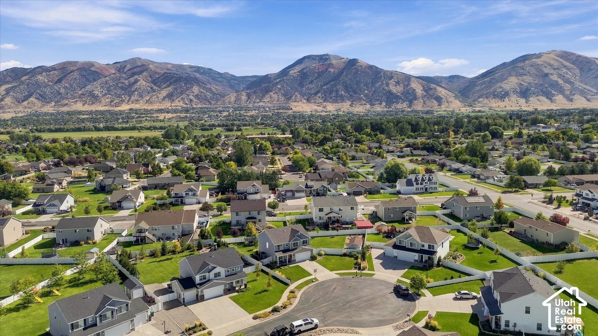 Residential neighborhood with multiple detached homes, paved streets, and green landscaping