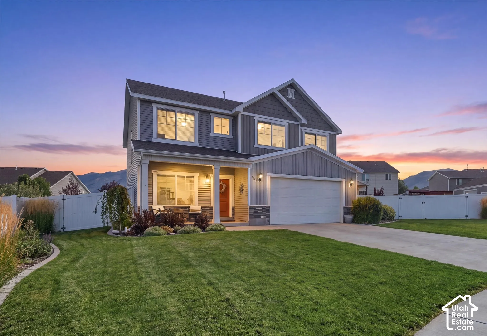 Two-story exterior with a covered front porch, attached garage, stone accents, and a fenced backyard